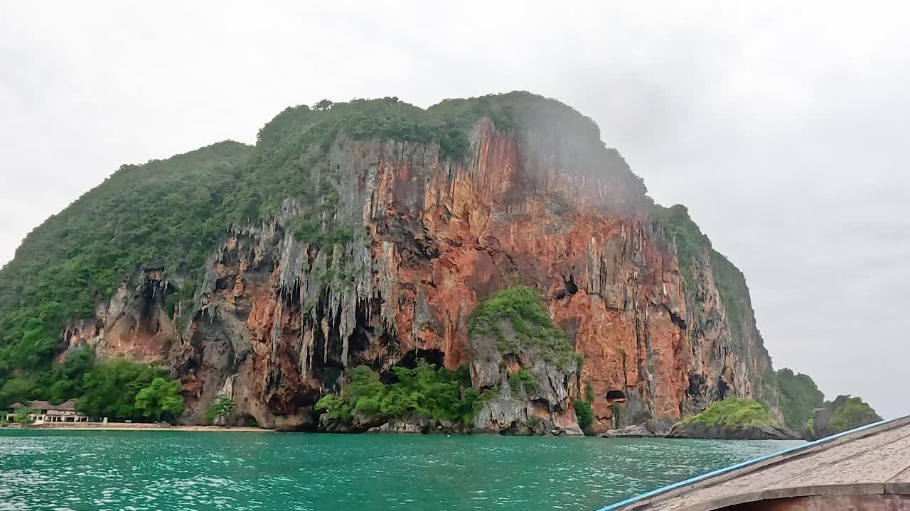 보트 가 울창 한 절벽 이 있는 경치 좋은 섬 에 접근 하고 있다