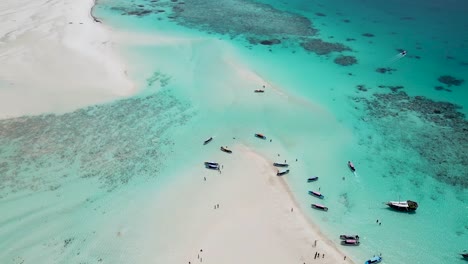 atoll at mnemba island of zanzibar,tanzania africa with snorkeling tour boats on the reef beach, aerial dolly up shot
