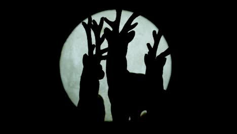 silhouetted miniature reindeer family standing against moonlight backdrop