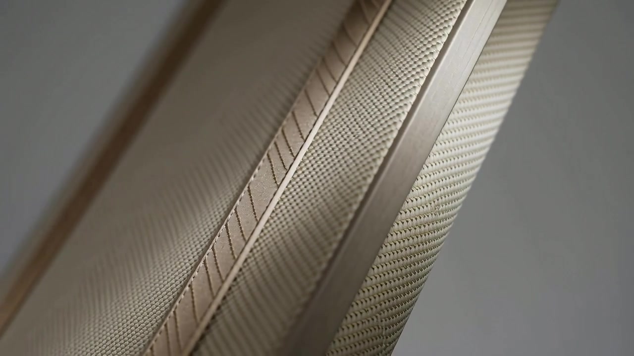 Moving camera examining gold-toned metallic cylinder in neutral studio, revealing band and seam
