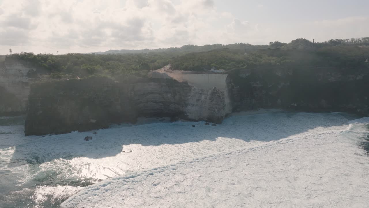 video de avión no tripulado de la destrucción ambiental de los acantilados de piedra caliza cerca del templo de pura luhur uluwatu, bali, indonesia, con excavadoras, excavación masiva de tierra y océano contaminado