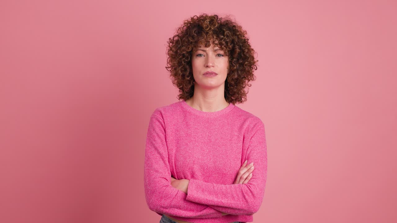 Disagreeing young woman shaking head with twisted mouth on pink background