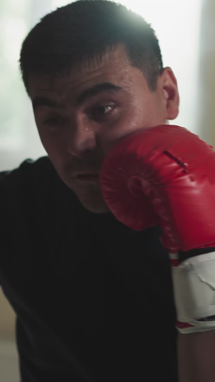 el boxeador golpea una bolsa pesada en un club deportivo. el deportista profesional hace ejercicios con equipos de lucha en el gimnasio en cámara lenta. campeón de artes marciales