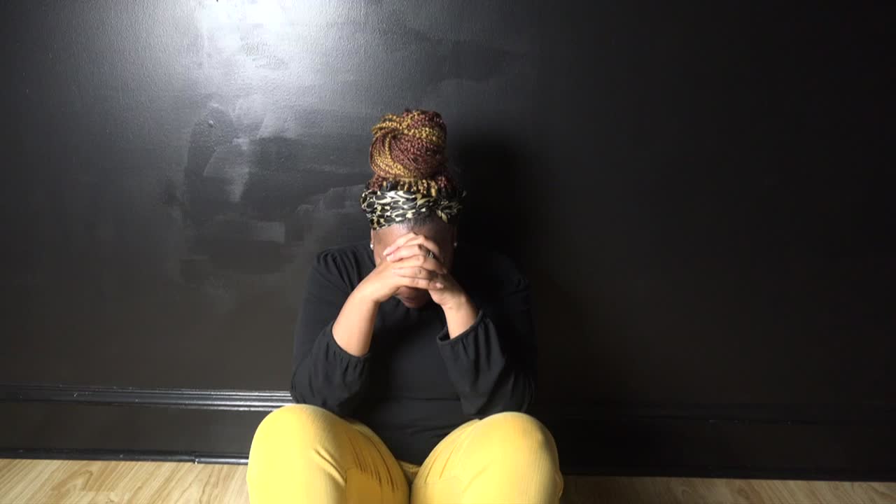 Black Woman dressed casually sitting down praying to God for peace and guidance