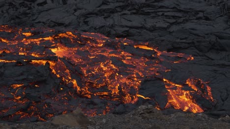 una corriente brillante de lava incandescente que fluye en un paisaje desolado