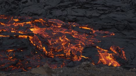 glowing stream of incandescent lava flowing in desolated landscape