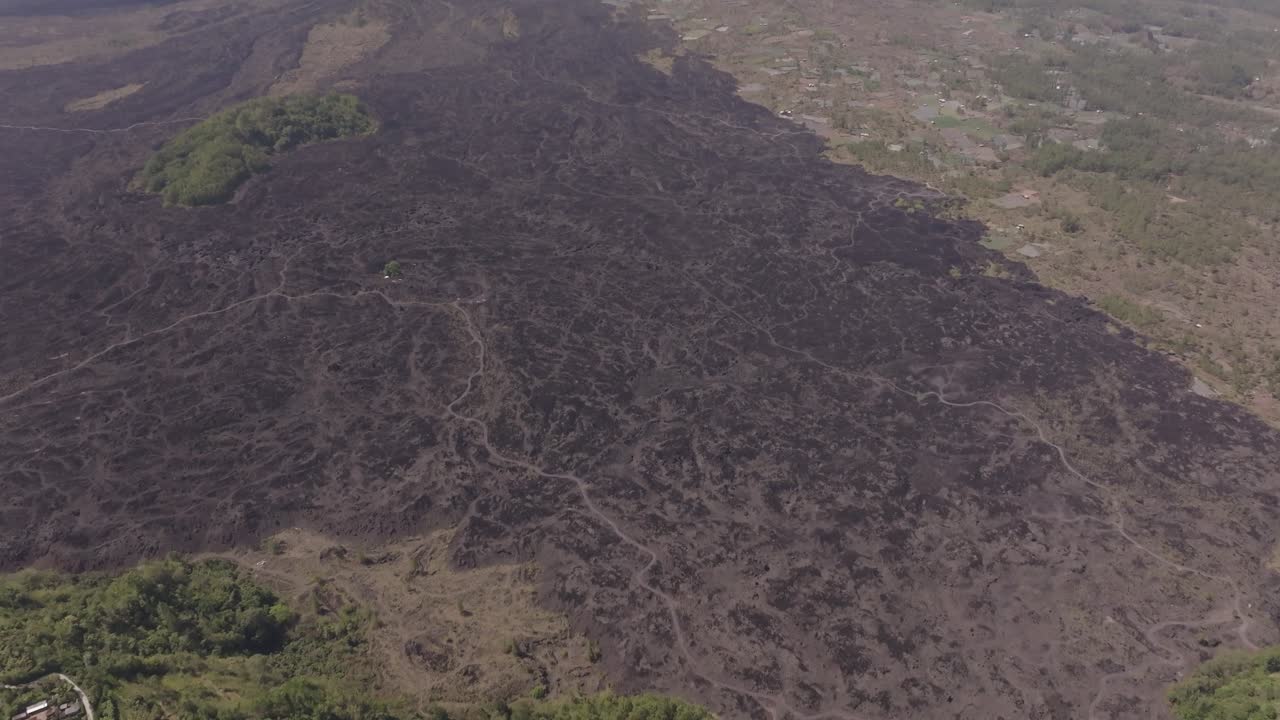Una ripresa con drone in 4k che si muove in panoramica dalle conseguenze vulcaniche del Monte Batur fino alla sua cima