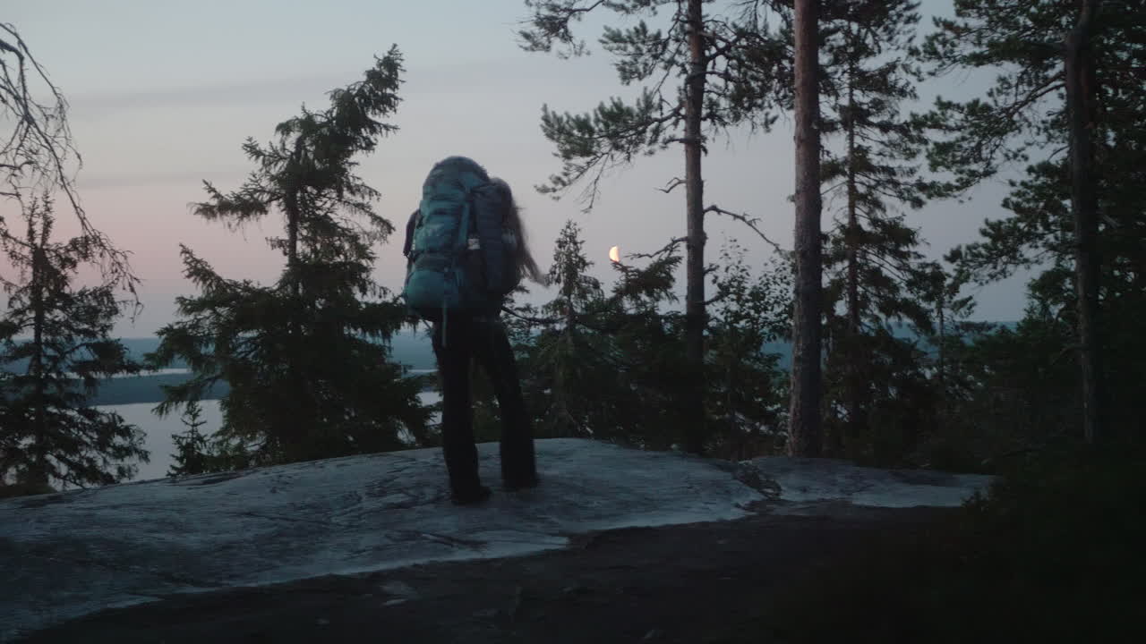 chica rubia nórdica caminando en una hermosa y pacífica atmósfera de crepúsculo, excursionista femenina caminando por la noche, parque nacional de koli, finlandia