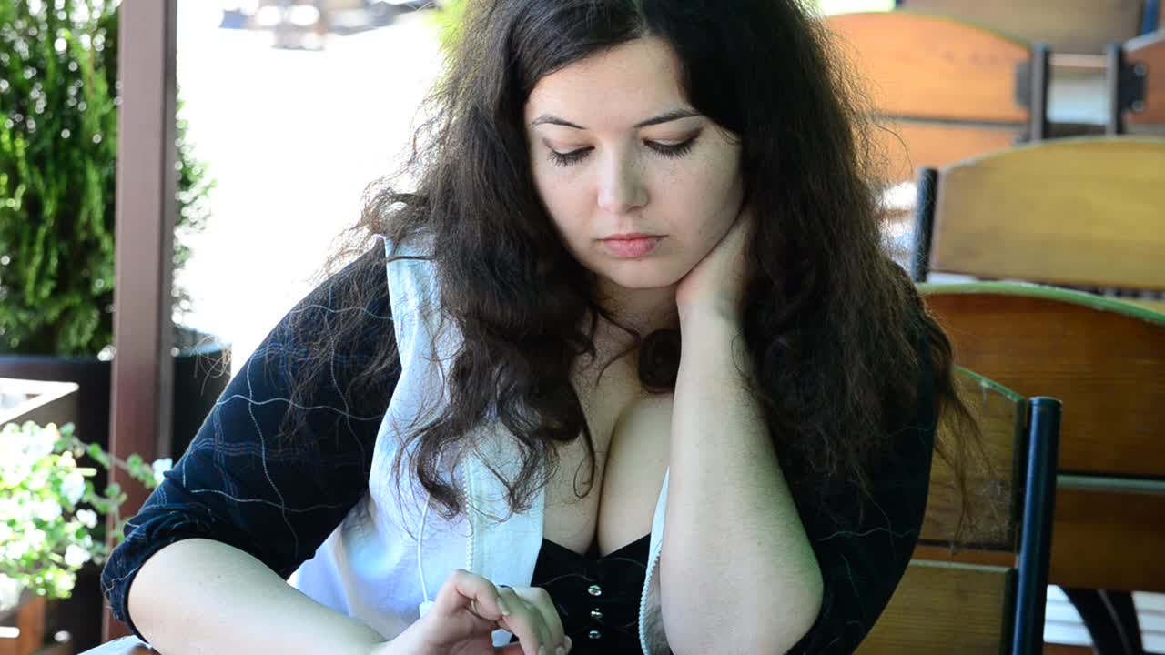 A garota toma café e trabalha no tablet. Filmagem da garota no café.