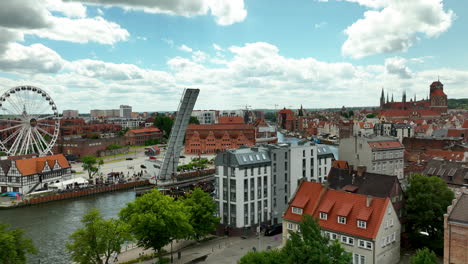 Aerial-view-of-Gdańsk-featuring-the-Motława-River,-a-modern-Ferris-wheel,-and-historic-buildings