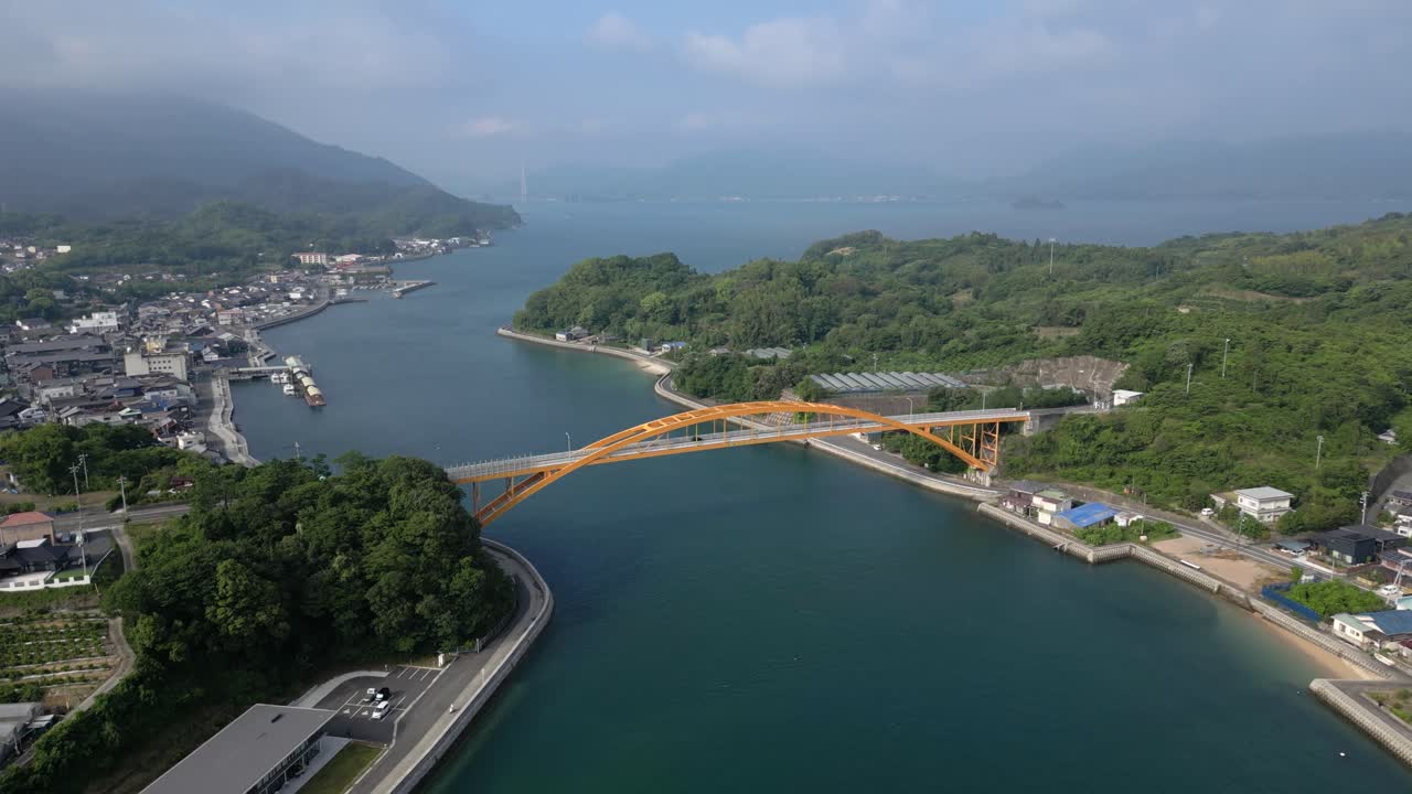 Slow cinematic drone tilt up over Seto Inland sea with yellow bridge