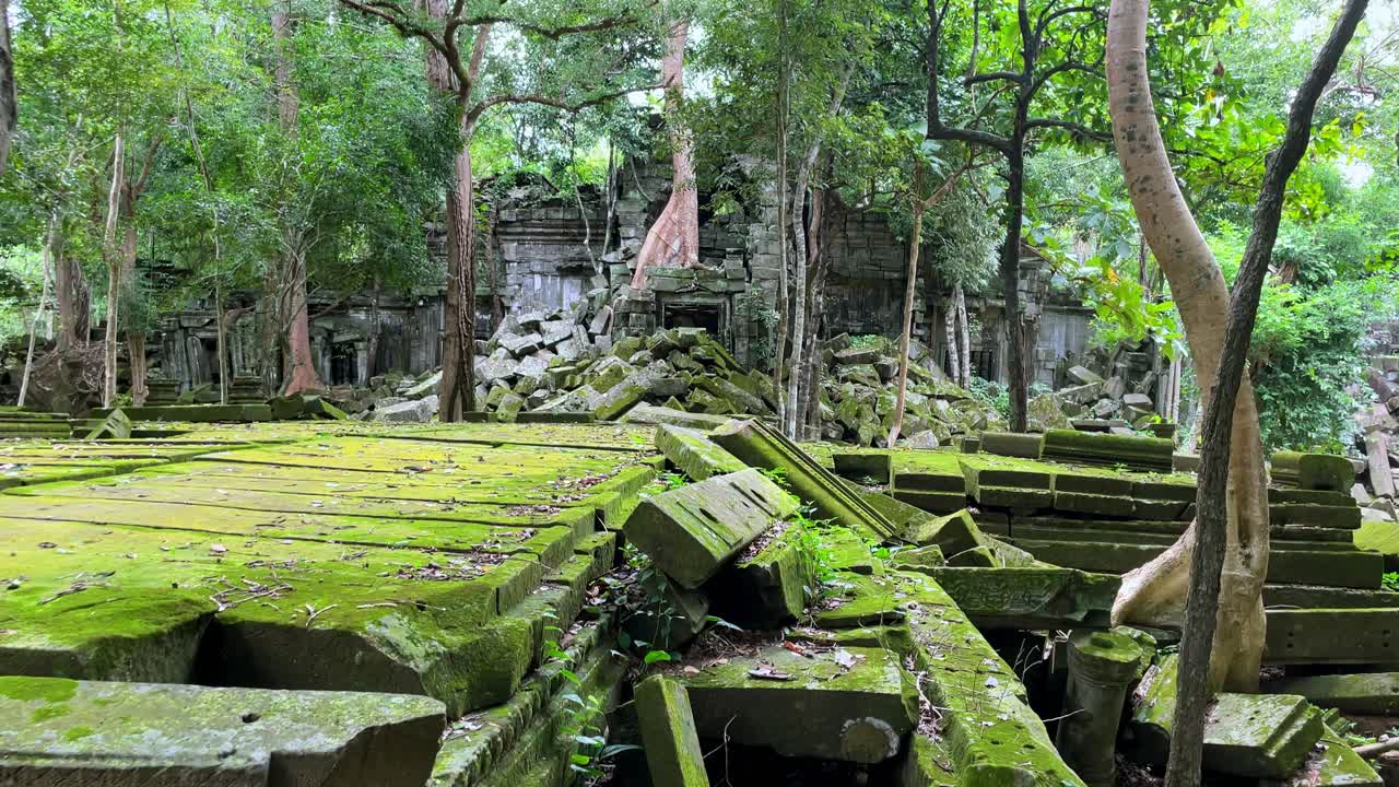 Tilt up establishing of the mossy ruins of the Prasat Beng Mealea temple in Cambodia on a sunny day, tourist site in the middle of the forest
