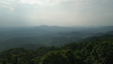 Montañas-Y-Colinas-En-El-Horizonte-Con-La-Puesta-De-Sol,-Un-Bosque-Verde-Y-Exuberante-En-Primer-Plano