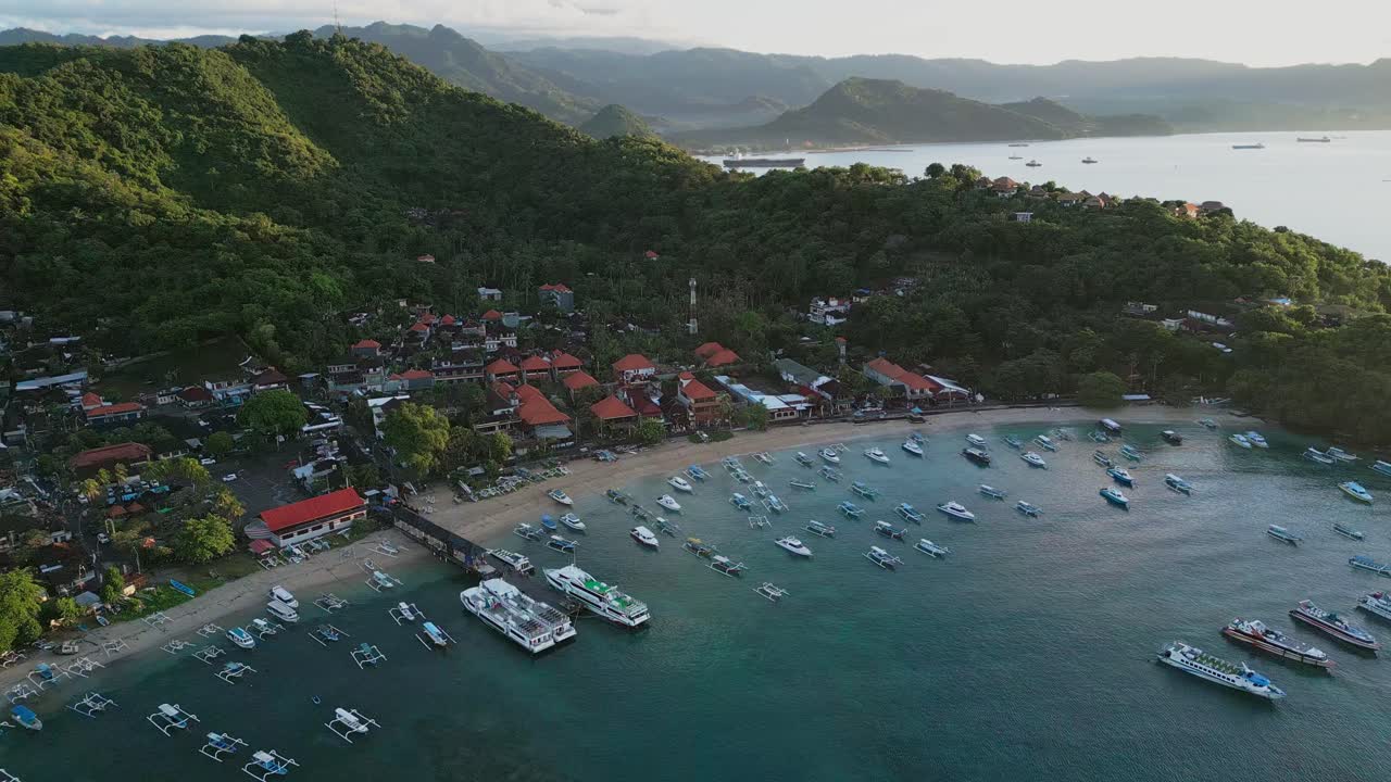 Traditional boats rest on the beach in Padang Bai Bali as the early morning sun lights up the hills creating a peaceful coastal scene with calm water and a gentle tropical atmosphere.