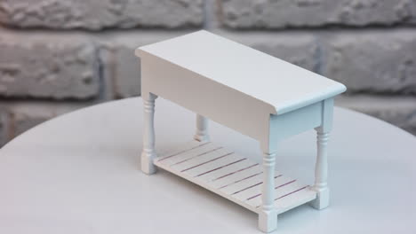 White piece of miniature furniture. Cute wooden table with drawers rotating. Close up.
