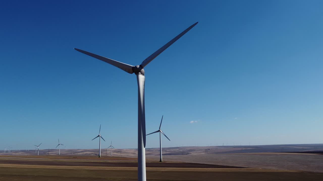 Grandi pale di turbine eoliche che ruotano al vento contro un cielo blu, in un parco eolico.
