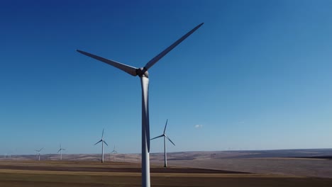 large blades of wind turbine spinning in wind against blue sky, wind farm