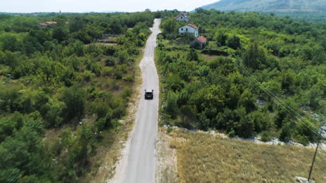 sobrevuelo aéreo de un coche conduciendo por una carretera rural en las montañas cerca de ljubuski en bosnia y herzegovina