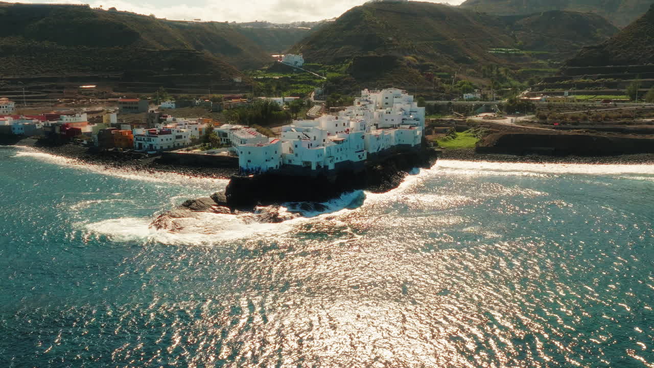 Aerial parallax view of Tejeda town with hills at background and sea in front in Spain.