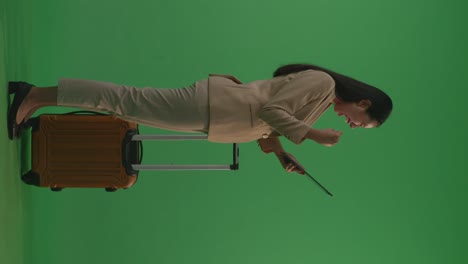 businesswoman with laptop and luggage on green screen