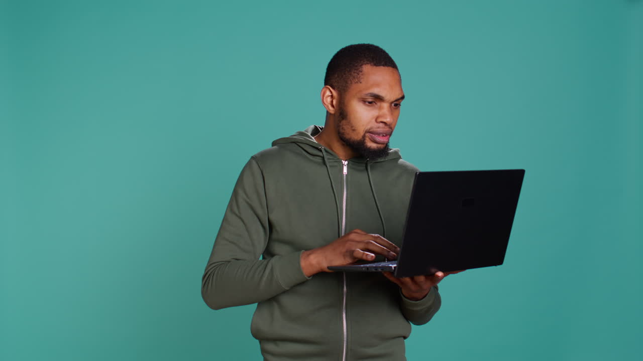 Man typing on laptop keyboard, checking emails, overjoyed by good news