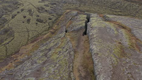 Aerial-of-open-solid-lava-field-in-Iceland,-rugged-terrain-of-earth