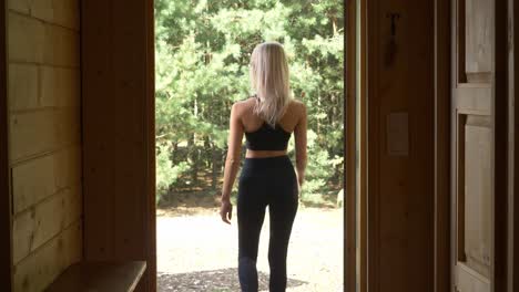 Slim-Fit-Woman-Wearing-A-Sportswear-Walks-On-The-Open-Door-In-Arendel-Norwegian-Village,-Zagorow,-Poland