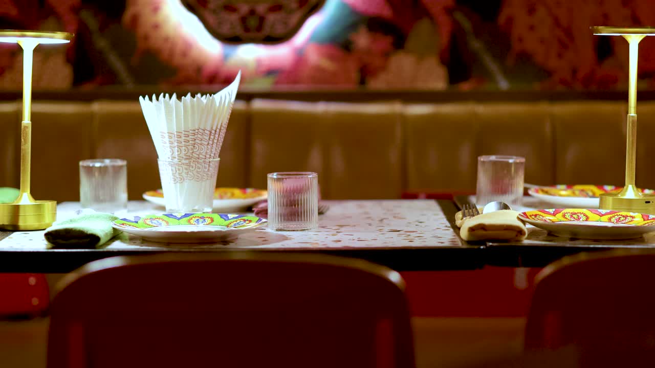 Neatly arranged tableware under warm lighting in a colorful, modern Bangkok restaurant interior