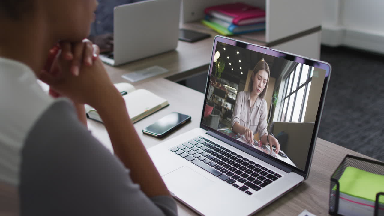 Mid section of african american woman having a video call on laptop with female colleague at office
