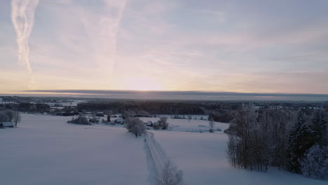 Toma-Aérea-Del-Cielo-De-La-Puesta-De-Sol-Vívida-Sobre-El-Paisaje-Boscoso-Cubierto-De-Nieve---Impresionante-Paisaje-De-Invierno-Blanco