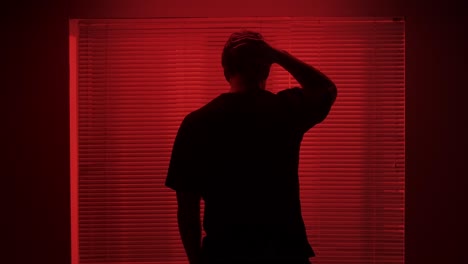 man looking out of a window in red light