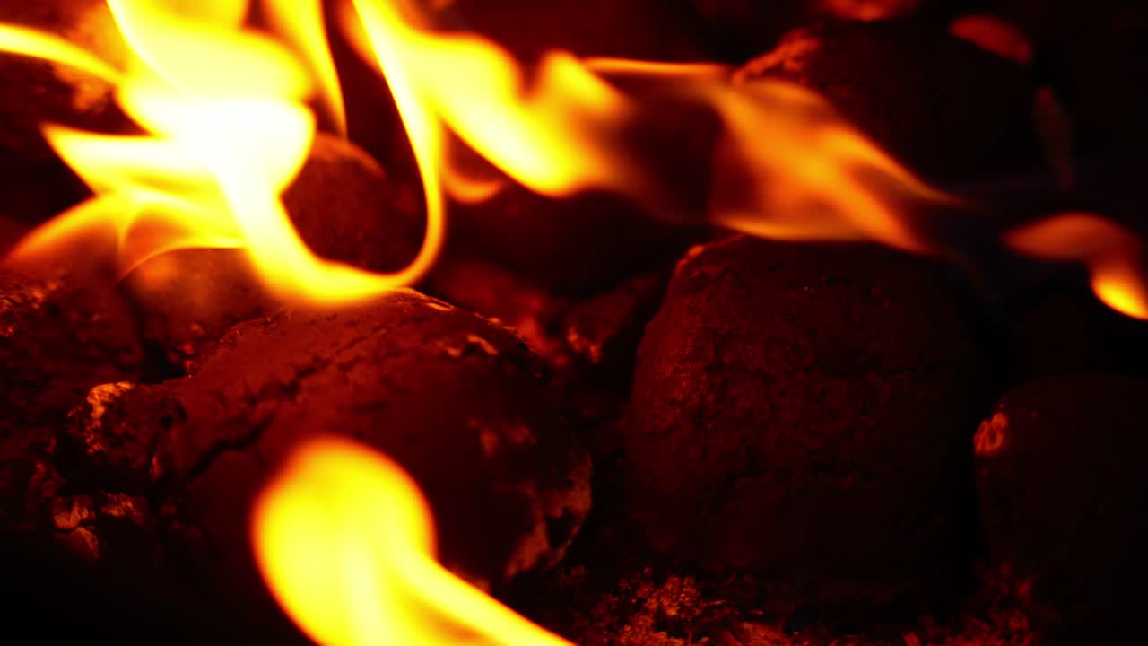 Coal briquettes burning background close-up with yellow orange flames