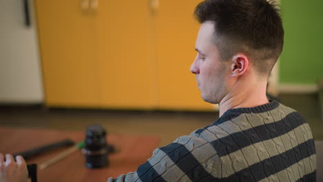 man adjusting video camera on tripod, preparing for filming in home studio. focused on equipment setup with green walls and cozy space in background, ready for content creation or media work