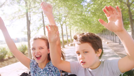 two kids have fun standing up and waving through car sunroof