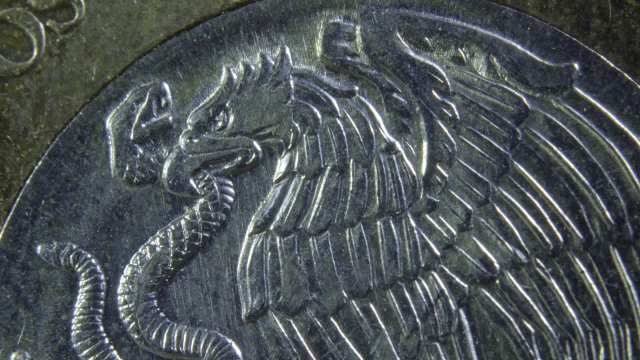 Zoom out revealing the detailed engraving of a Mexican ten-peso coin under bright light