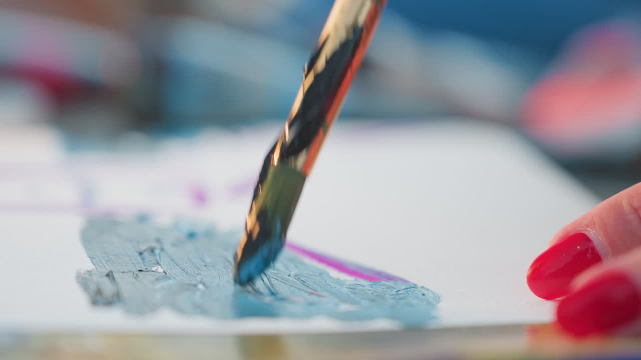creative hands of mature woman with red nails guide brush across white sheet, applying vibrant paint strokes and blending colors in close up artistic process capturing texture and motion