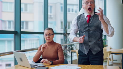 secretary and her mature boss in office. senior businessman puts document on the desk angrily and feels ashamed. slow motion.