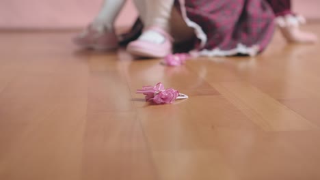 빈티지 버곤디 드레스를 입은 귀여운 작은 소녀가 헤어 클립으로 놀고 있습니다.