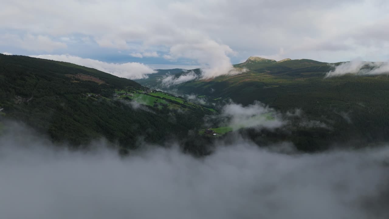 vista aérea de colinas verdes y valles parcialmente cubiertos por nubes, creando un paisaje sereno y pacífico