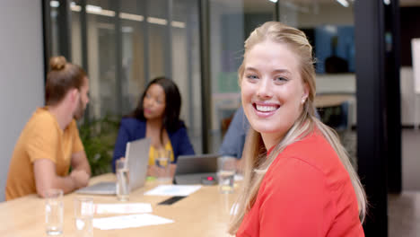 Portrait-of-happy-caucasian-casual-businesswoman-with-diverse-colleagues-at-office-meeting