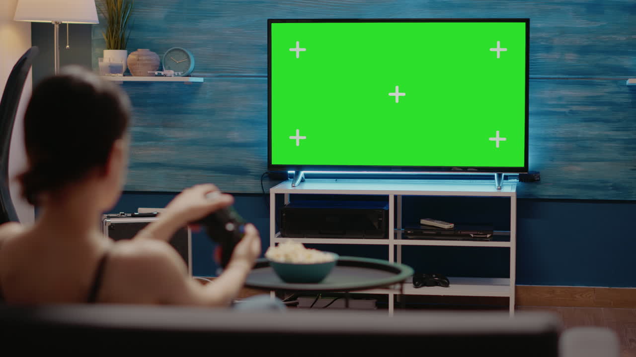Young woman using controller on green screen on tv