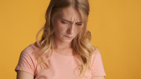 una mujer caucásica usando un teléfono inteligente y entristeciéndose.