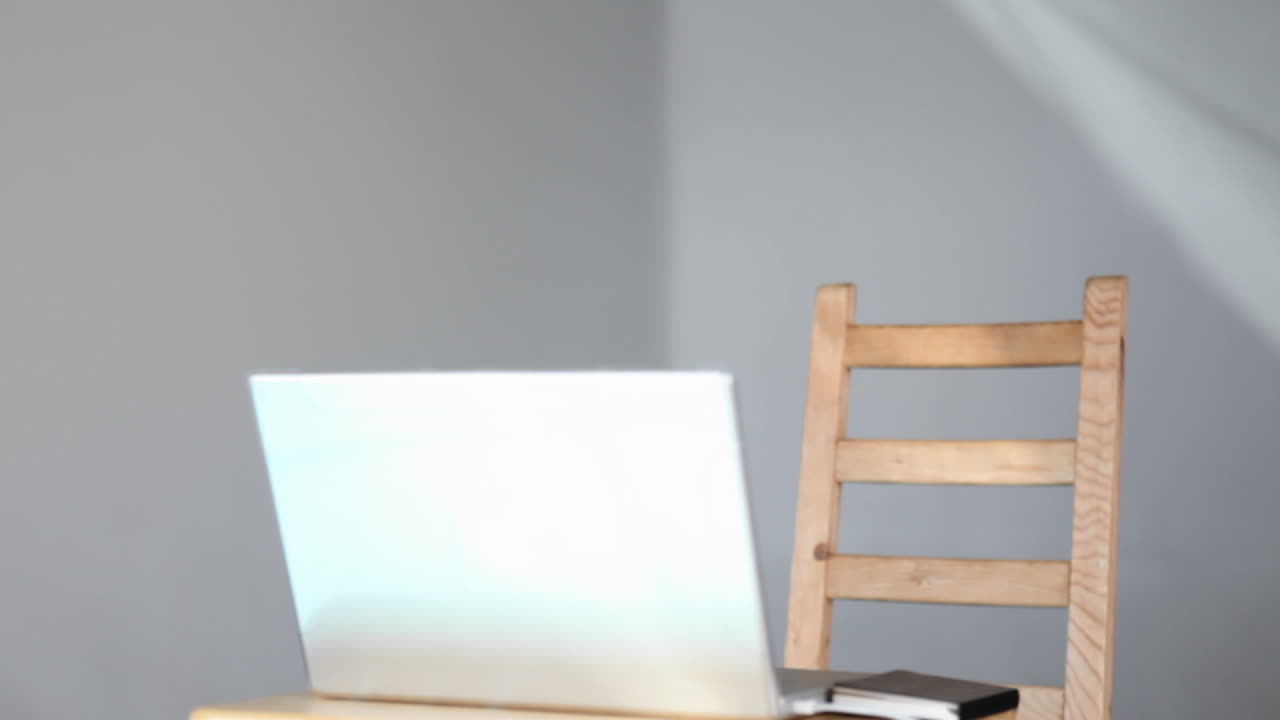 un joven se sienta y sonríe mientras comienza a usar su computadora portátil