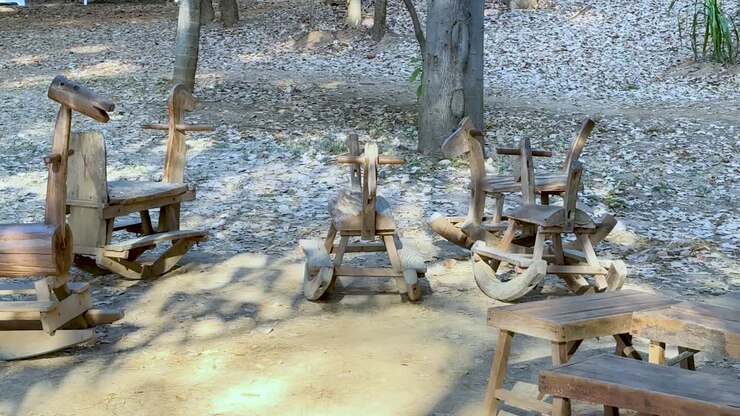 holzrockpferde unter bäumen in einem park