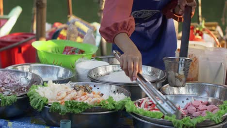 Este-Atractivo-Material-De-Archivo-Captura-A-Una-Mujer-Tailandesa-Preparando-Meticulosamente-Los-Ingredientes-Para-Cocinar-En-El-Bullicioso-Mercado-Flotante-De-Hat-Yai,-Tailandia.