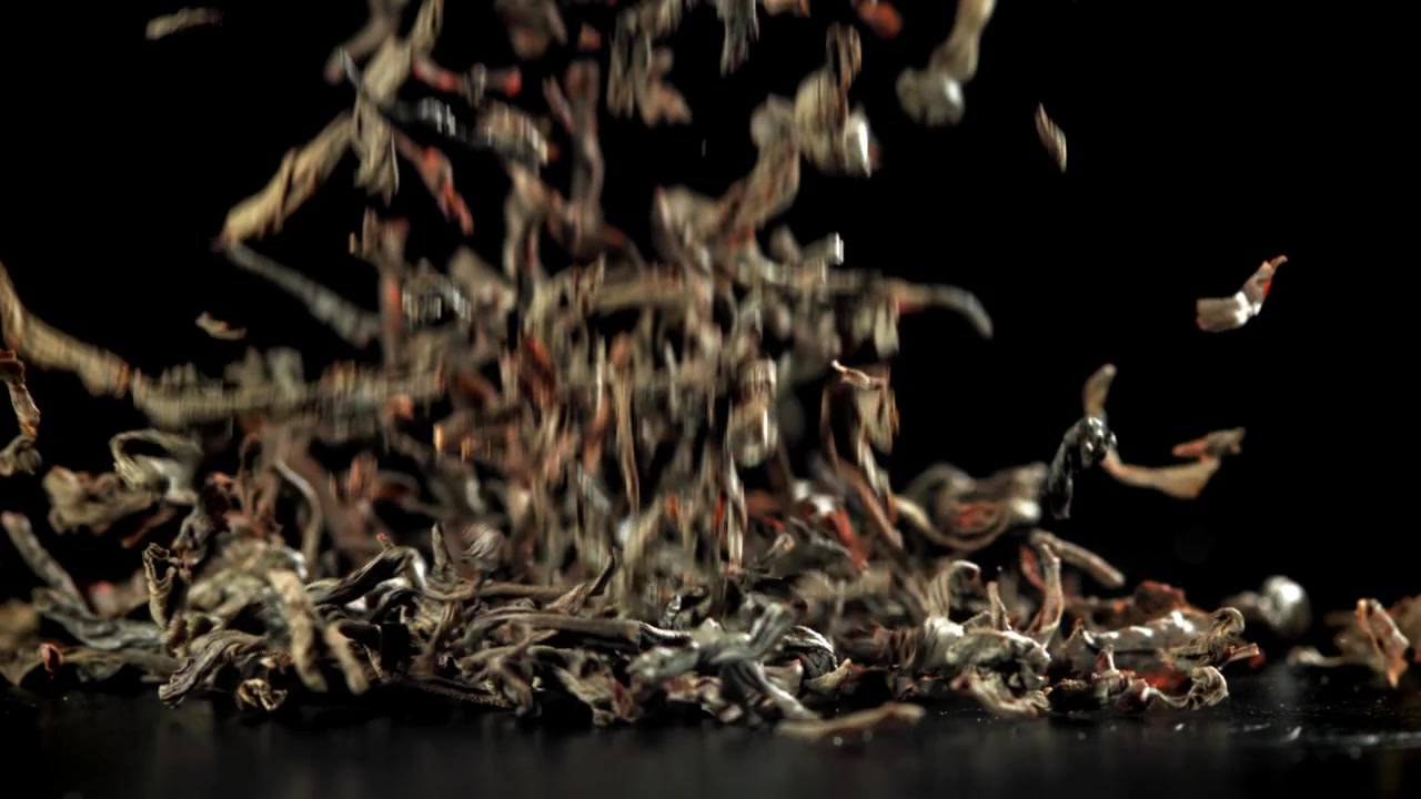 Dried Tea Leaves Falling in Slow Motion on Black Background