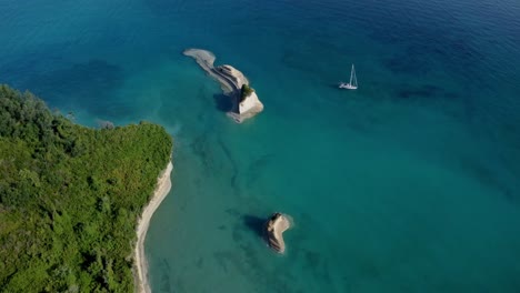 sail boat cruising the mediterranean ocean moored on the coastline of corfu island in greece, aerial view
