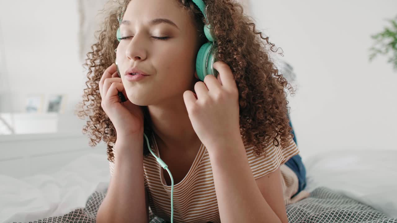 una mujer joven escuchando música en su cama.