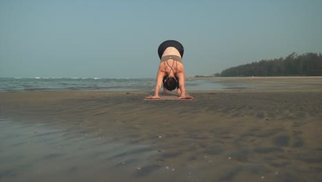 solo caucasian woman in calming yoga pose, stretches on the beach