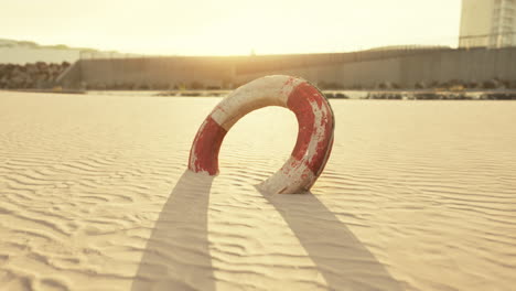 lonely lifebuoy on a sandy beach at sunset